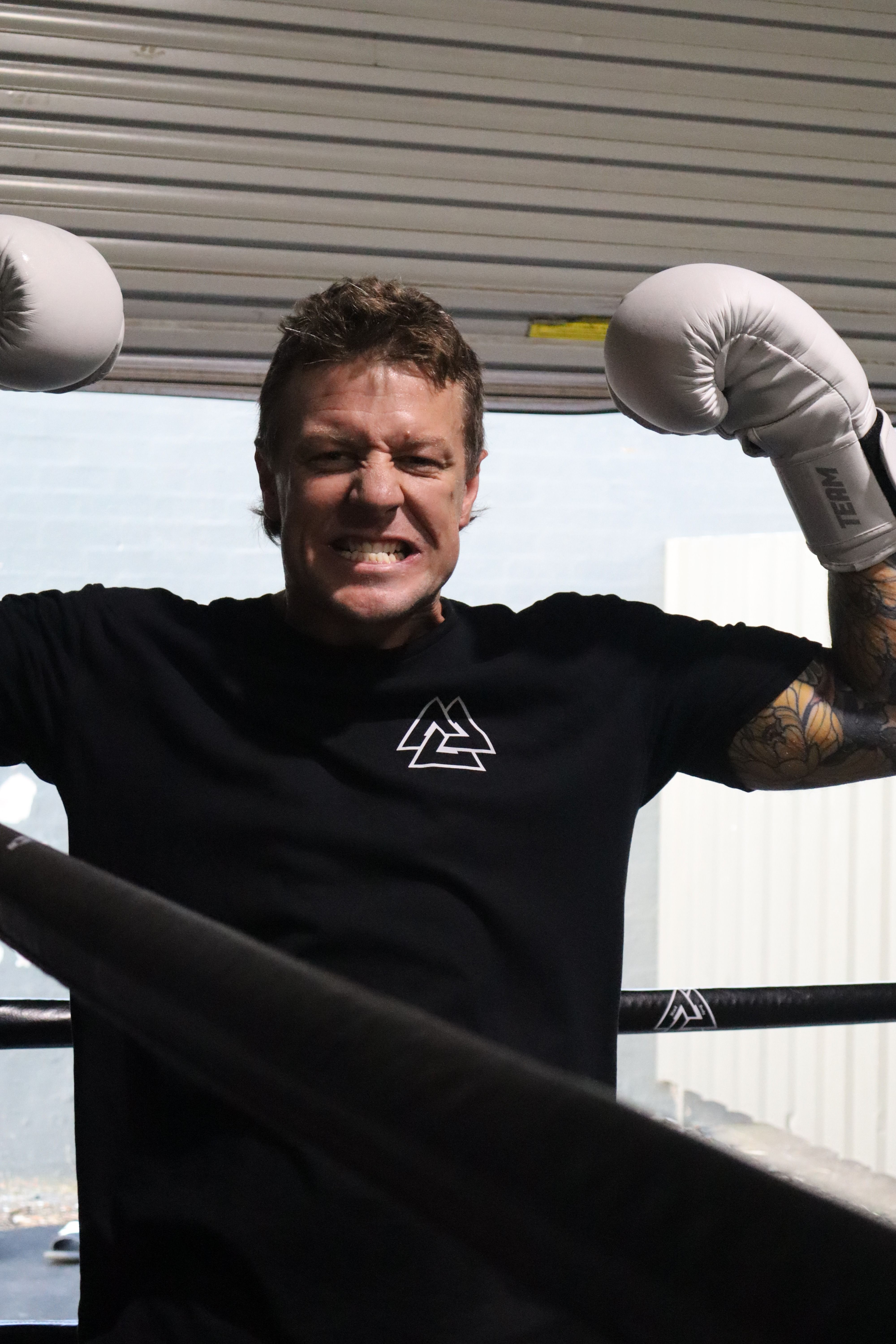 A member grinning with gloves up in the ring