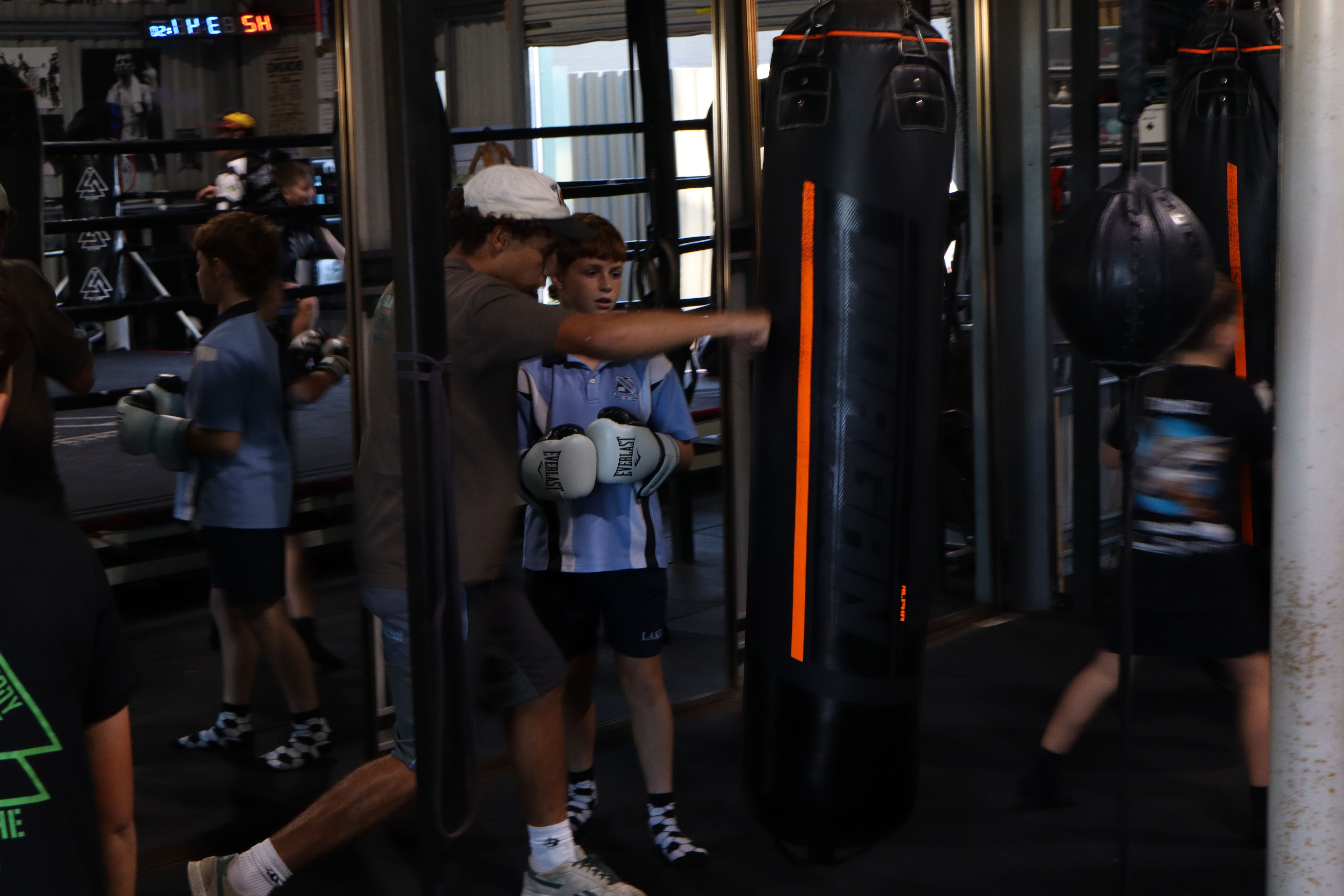 Coach guiding a young boxer at the bag at Box & Breathe