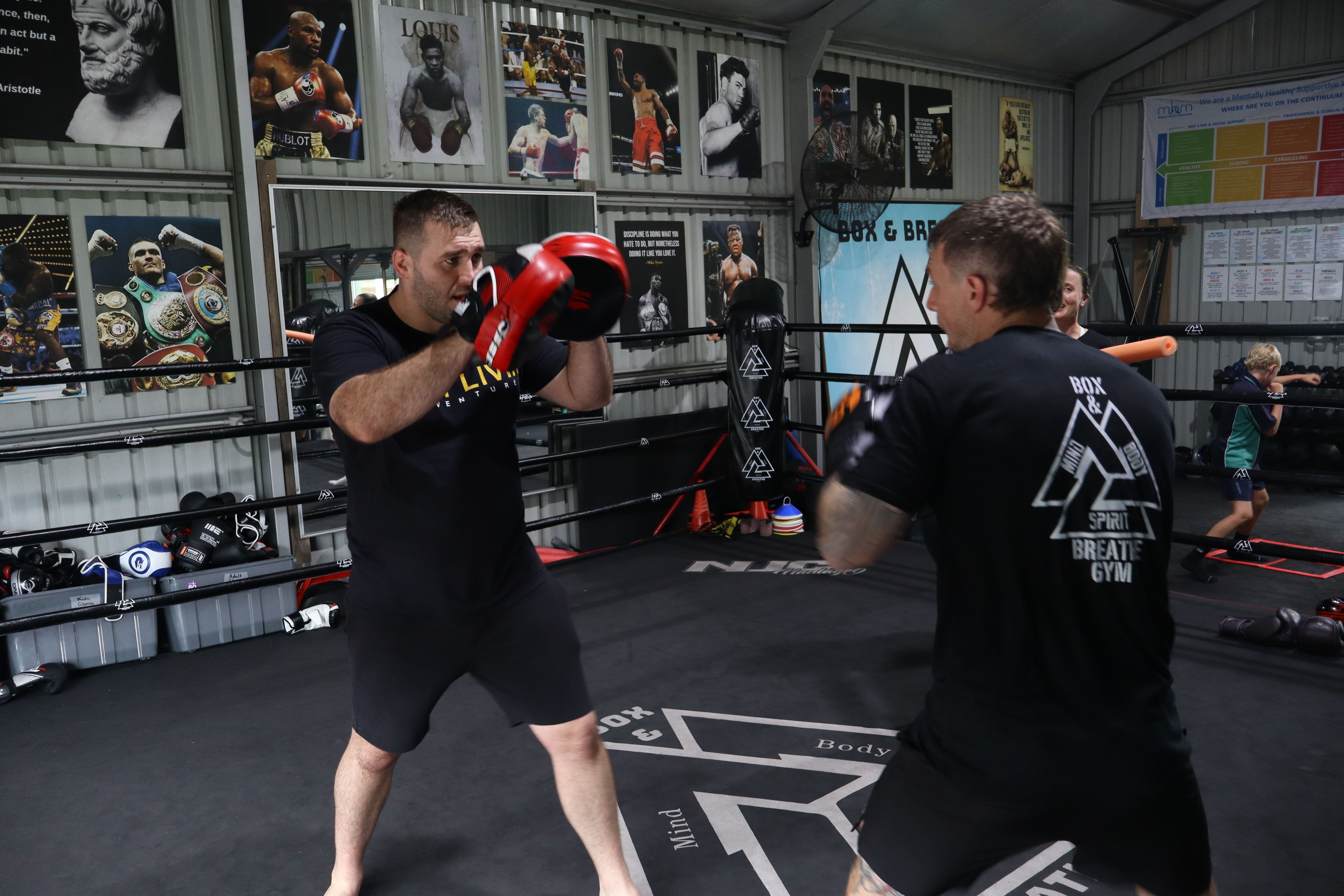 A coach holding pads for a boxer in the ring